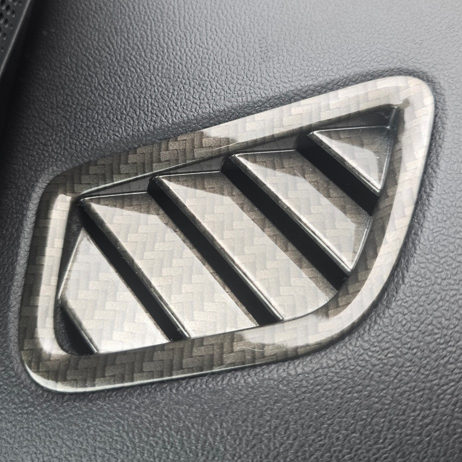 Carbon fiber patterned car emblem on a gray leather surface